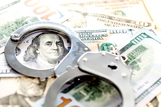 Handcuffs lying on american dollars Handcuffs lying on american dollars, financial crime concept. money laundering stock pictures, royalty-free photos & images