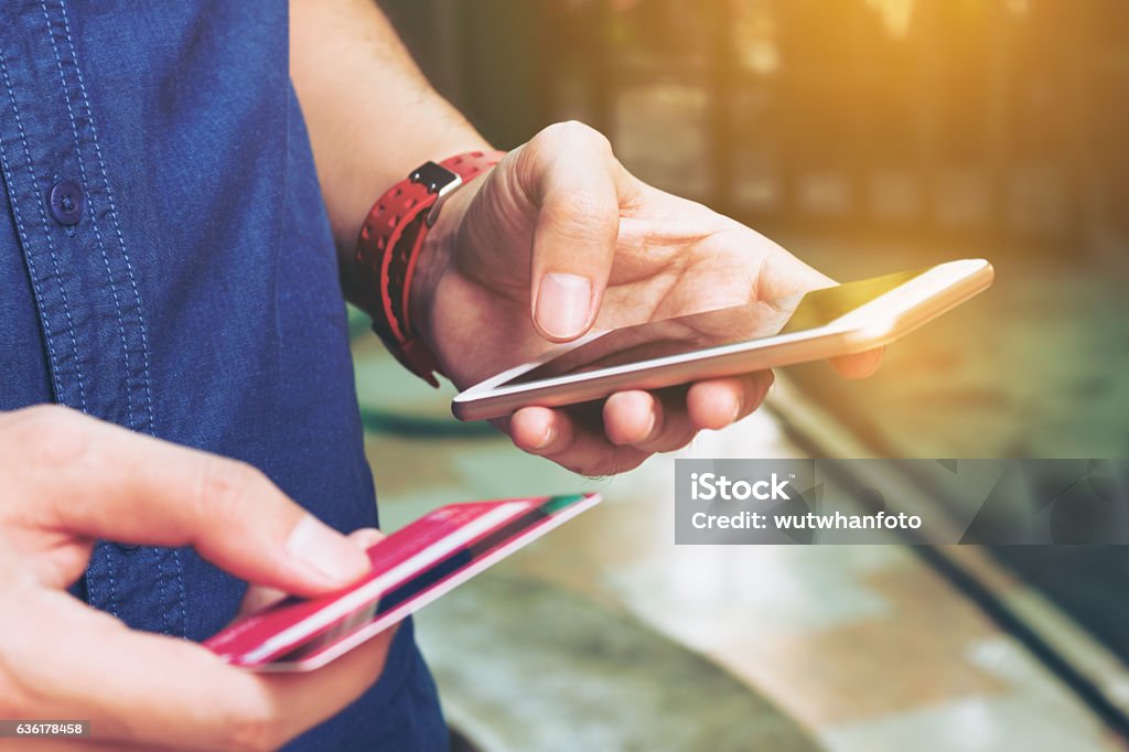 Hombre usar el teléfono inteligente y la celebración de la tarjeta de crédito con las compras - Foto de stock de Tarjeta de crédito libre de derechos