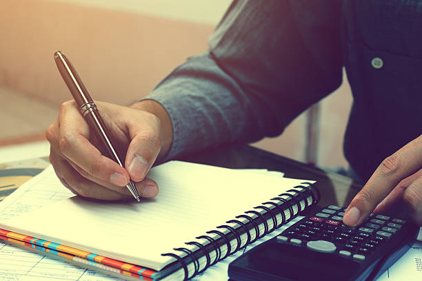 istock Asian young man doing finances with using calculator and writing 636179858