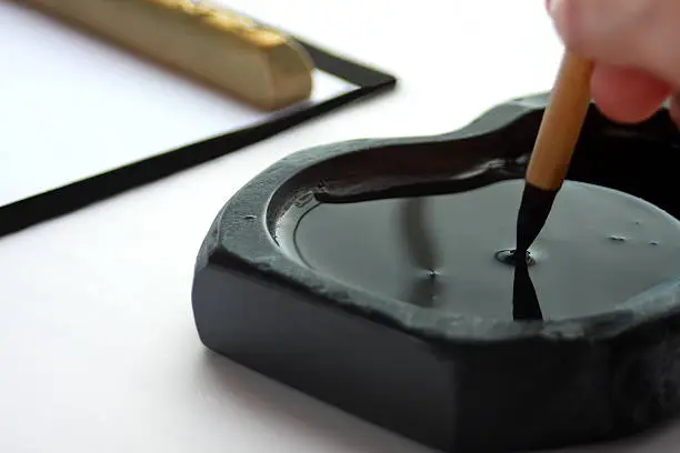 a calligraphy scene in which ink ink is attached to a brush and a character is written on half paper