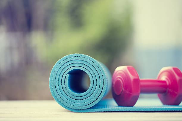 dumbbell and yoga mat on wood table dumbbell and yoga mat on wood table exercise mat photos stock pictures, royalty-free photos & images
