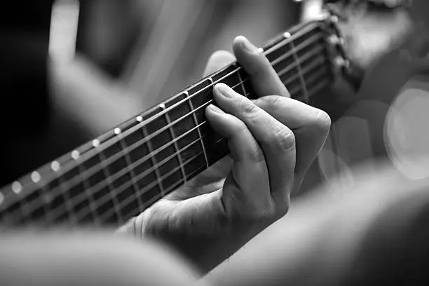 Photo of Musician's fingers on the strings of a guitar closeup