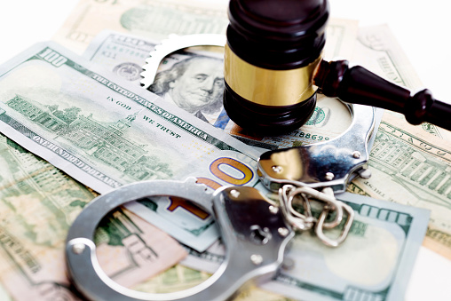 Judges gavel and handcuffs on american dollars, financial crime concept.