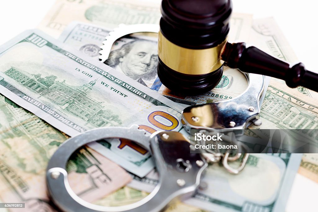 Judges gavel and handcuffs on american dollars Judges gavel and handcuffs on american dollars, financial crime concept. Money Laundering Stock Photo