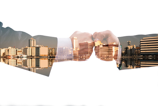 Businessmen fists and city scape double exposure image.