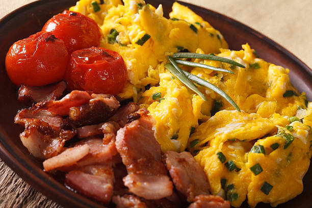istock Scrambled eggs with green onions, bacon and tomatoes close-up 636194182