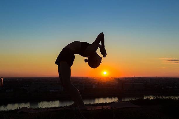 istock Woman practicing yoga at sunset - drop back, wheel pose 636196232