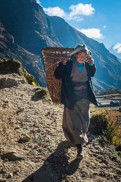 竹のバスケットヒマラヤ山道ネパールを運ぶシニアシェルパの女性 - namche bazaar ストックフォトと画像