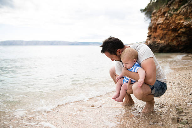 Man with his baby son at the beach having fun.
