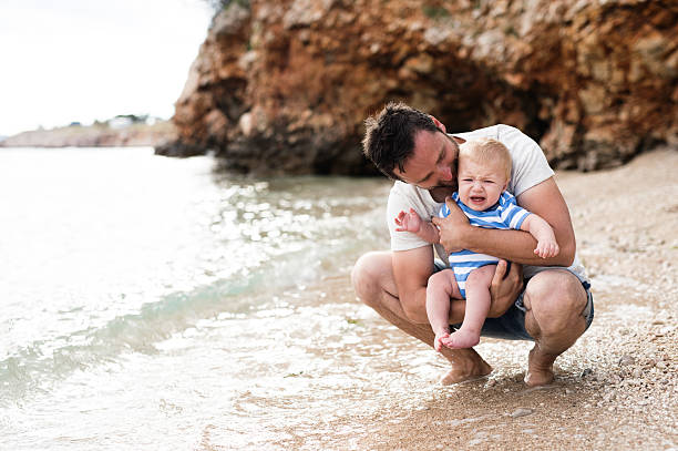 istock Man with his baby son at the beach having fun. 636197524