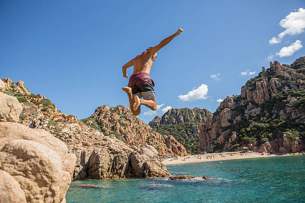 istock Young man jumps off the cliff into the sea 636197744