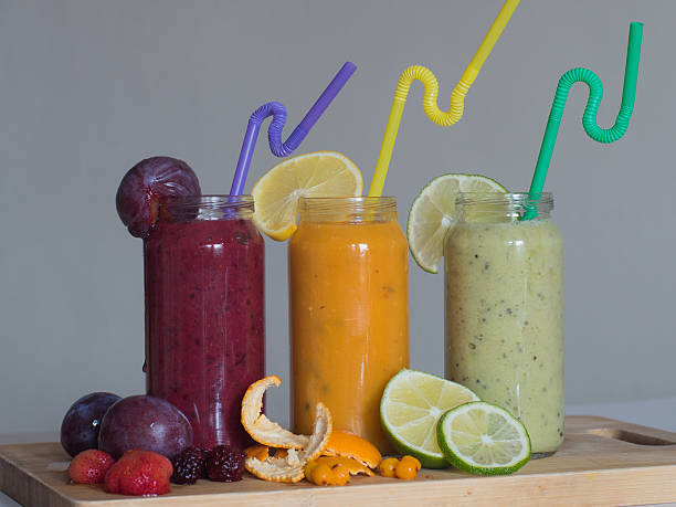 istock Fresh raspberry, banana, spinach and orange drinks on wooden table. 636198874