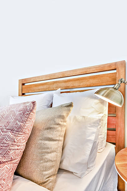 istock Luxury wooden bed with pillows close up beside a lamp 636201080