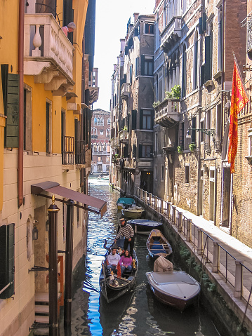 Venice, Italy - September 14, 2007: Traditional gondola boat on narrow canals of Venice through Venetian alleys. Italian city of Unesco Heritage.
