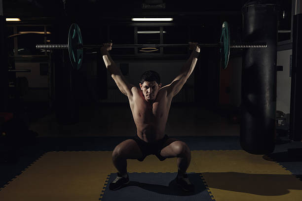 istock Muscular man at a gym gym lifting a barbell. 636201954
