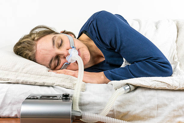 mujer durmiendo de lado con la máquina de cpap. - apnea del sueño fotografías e imágenes de stock