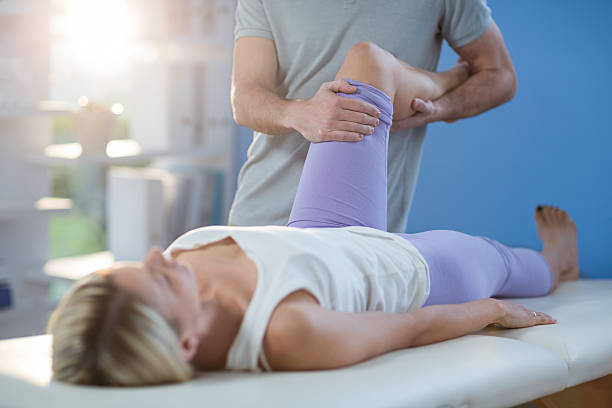 Male physiotherapist giving knee massage to female patient Male physiotherapist giving knee massage to female patient in clinic physical therapy recovery touching human knee stock pictures, royalty-free photos & images