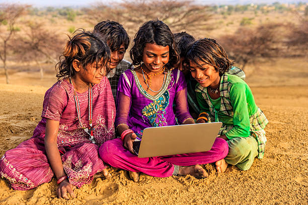 istock Happy Indian children using laptop, desert village, India 636208418