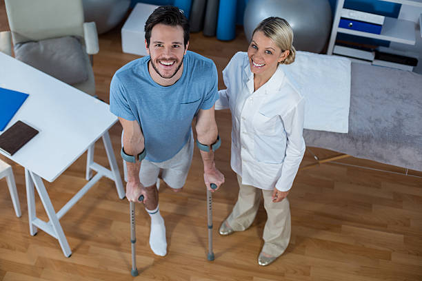 istock Physiotherapist helping patient to walk with crutches 636208560