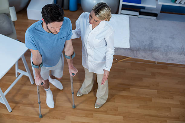 istock Physiotherapist helping patient to walk with crutches 636208636