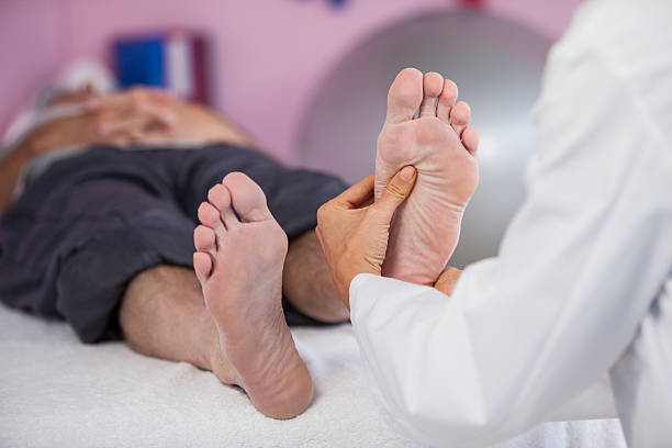 homme âgé recevant un massage des pieds d’un physiothérapeute - reflexology human foot physical therapy massaging photos et images de collection