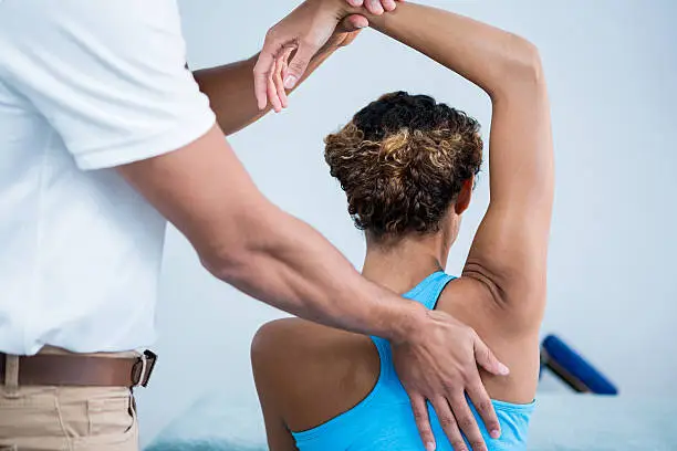 Physiotherapist giving shoulder therapy to a woman in clinic