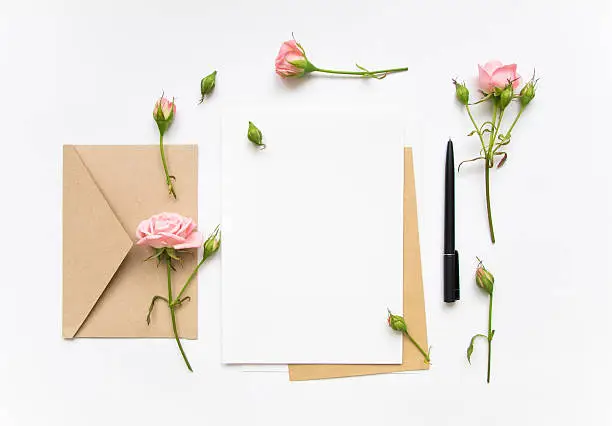 Photo of Letter and envelope decorated with pink roses. Holiday flat lay