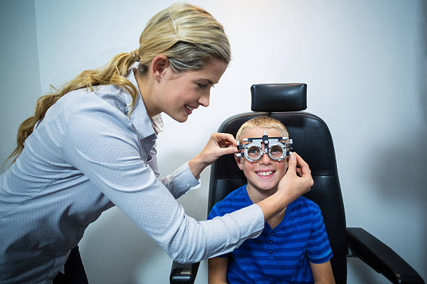 Female optometrist examining young patient with phoropter Female optometrist examining young patient with phoropter in ophthalmology clinic Messbrille stock pictures, royalty-free photos & images