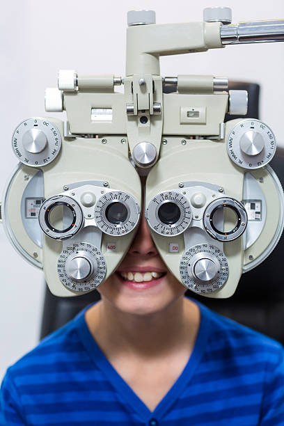 istock Young patient looking through phoropter during eye examination 636214466