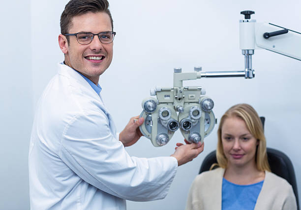 Smiling optometrist examining female patient on phoropter Smiling optometrist examining female patient on phoropter in ophthalmology clinic Messbrille stock pictures, royalty-free photos & images