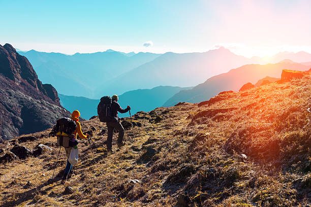 istock Hikers with Backpacks walking in Mountains towards rising Sun 636214682