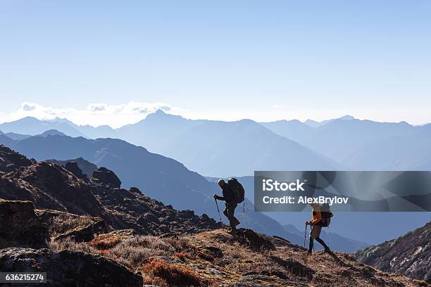 People With Backpacks And Trekking Sticks Traveling In Mountains Stock Photo - Download Image Now