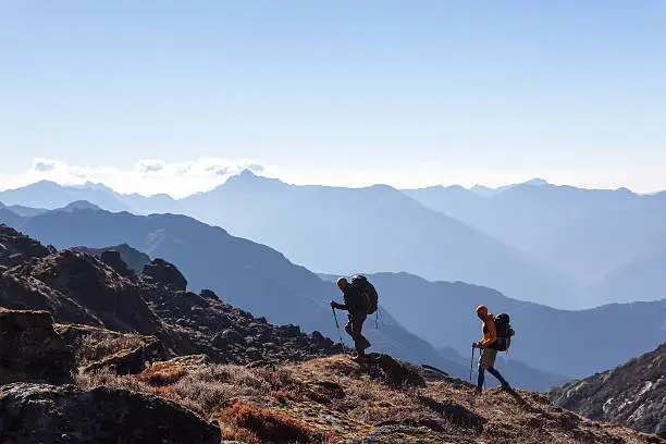 Photo of People with Backpacks and trekking Sticks traveling in Mountains