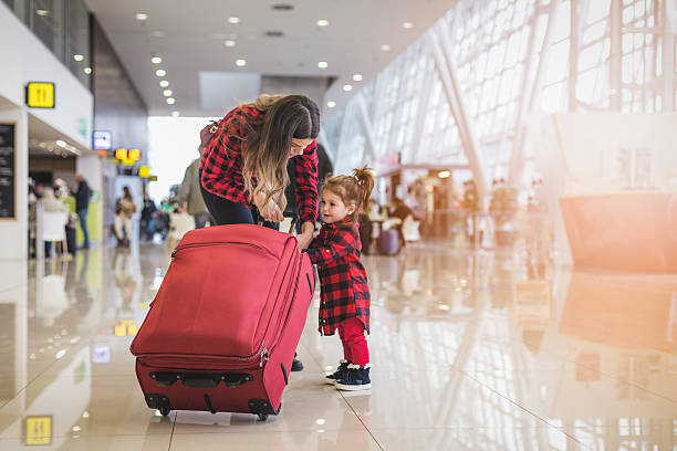 istock Mother and cute toddler girl pulling together a suitcase 636216492