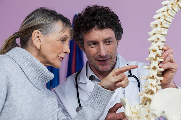 istock Physiotherapist explaining the spine model to patient 636218260