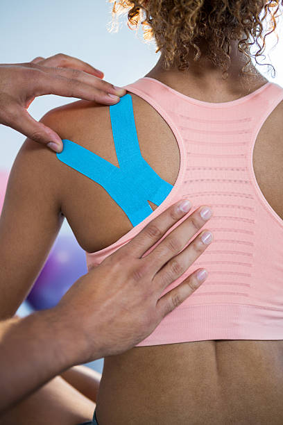 physiotherapist sticking tape on female patient - kinesio imagens e fotografias de stock