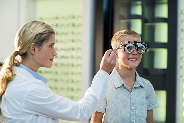 Female optometrist examining young patient with phoropter Female optometrist examining young patient with phoropter in ophthalmology clinic Messbrille stock pictures, royalty-free photos & images