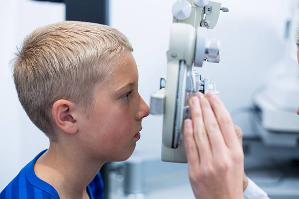 Young patient under going eye test through phoropter Young patient under going eye test through phoropter in ophthalmology clinic Messbrille stock pictures, royalty-free photos & images