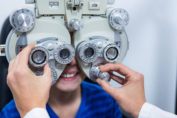 Young patient under going eye test through phoropter Young patient under going eye test through phoropter in ophthalmology clinic Messbrille stock pictures, royalty-free photos & images