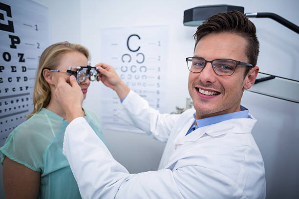 Optometrist examining female patient with phoropter Smiling optometrist examining female patient with phoropter Optometrist examining female patient with phoropter Messbrille stock pictures, royalty-free photos & images