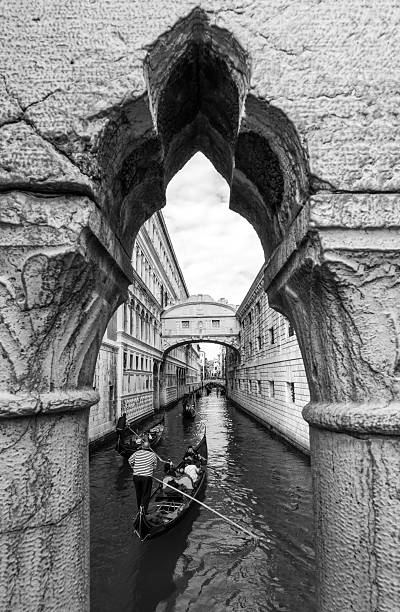 Venice, Italy - November 10, 2015:  Monochrome image of gondoliers rowing under the Bridge of Sighs in a foggy Venice