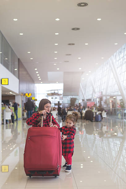 istock Mother and cute toddler girl pulling together a suitcase 636221892