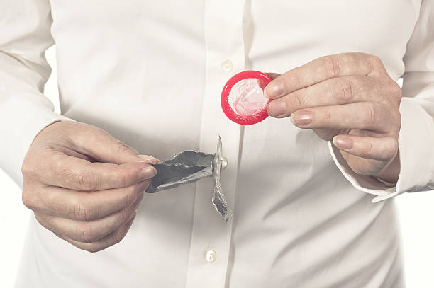 Female hands opening a new condom. stock photo
