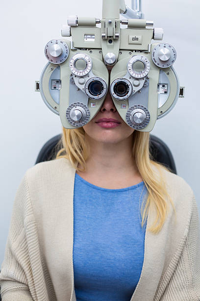 Female patient looking through phoropter during eye examination Female patient looking through phoropter during eye examination in ophthalmology clinic Messbrille stock pictures, royalty-free photos & images