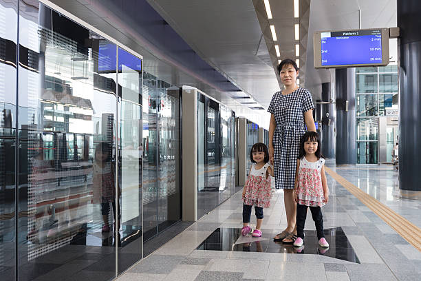 istock Asian Chinese mother and daughters waiting for transit at statio 636228084