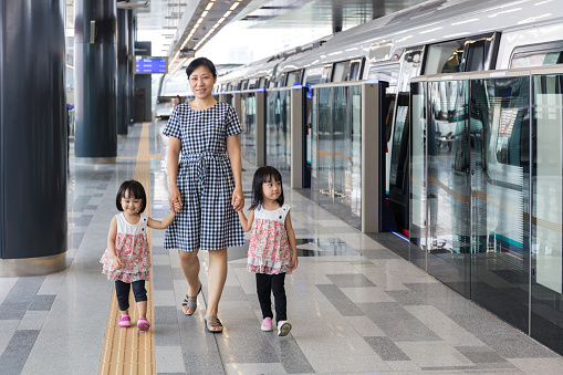 Asian Chinese mother and daughters waiting for transit at MRT station in Kuala Lumpur, Malaysia.