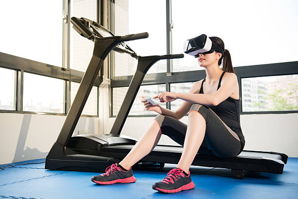 istock woman rest treadmill with VR headset control by smartphone 636230506