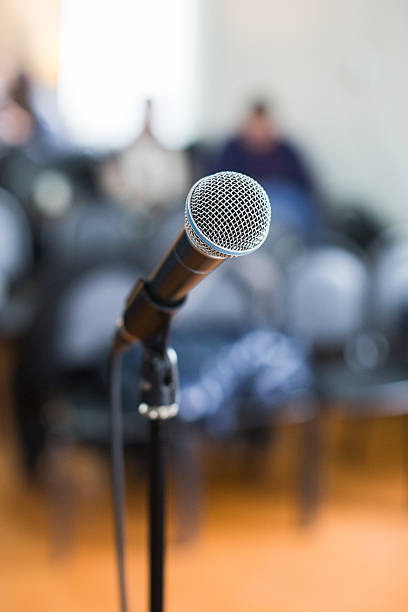 istock Vocal Microphone in focus against blurred audience at the conference 636230550