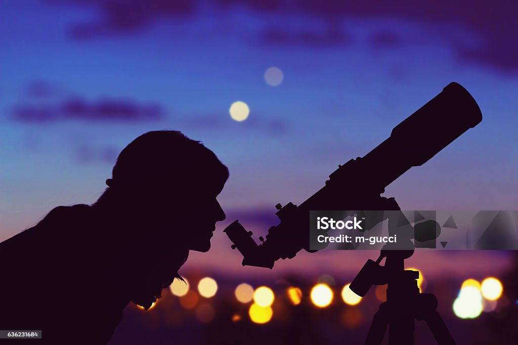 Girl looking at the stars with telescope beside her. Girl looking at the stars with telescope beside her and de-focused city lights. My astronomy work. Astronomy Stock Photo