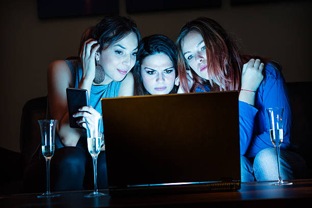 istock Three girlfriends, drinking champagne, watchng something interes 636236402